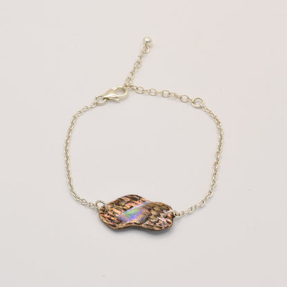 The Salty Dreamers Bracelet | Paua Shell One showcases a handmade, iridescent pāua shell centerpiece with a wavy, organic shape in 925 silver—an elegant piece of New Zealand jewelry shown on a white background.