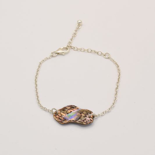 The Salty Dreamers Bracelet | Paua Shell One showcases a handmade, iridescent pāua shell centerpiece with a wavy, organic shape in 925 silver—an elegant piece of New Zealand jewelry shown on a white background.