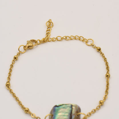 The Salty Dreamers Bracelet | Paua Shell Pae features a gold chain with a lobster clasp, extender, and central iridescent pāua shell bead—ideal for fans of handmade New Zealand jewelry. Displayed on a simple light background.