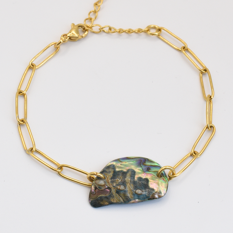 The Salty Dreamers Bracelet | Paua Shell Aroha showcases an iridescent pāua shell pendant on a gold chain with elongated links, celebrating handmade New Zealand abalone jewelry against a white backdrop.