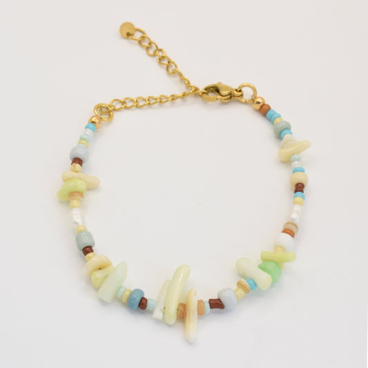 The Salty Dreamers Bracelet | Ocean Bamboo Rainbow features a gold chain with multicolored irregular handmade beads and small round beads in pastel green, blue, brown, and white for a casual, natural look.