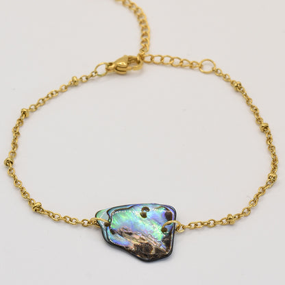 The Bracelet | Paua Shell Hau by Salty Dreamers features an iridescent, irregular-shaped pāua shell on a delicate gold chain—an elegant handmade New Zealand piece displayed on a plain white background.