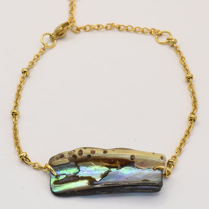 The Paua Shell Kaukau bracelet by Salty Dreamers features a gold chain and an iridescent rectangular paua shell centerpiece in natural brown and green hues, fastened with a lobster clasp—a refined piece of New Zealand jewelry.
