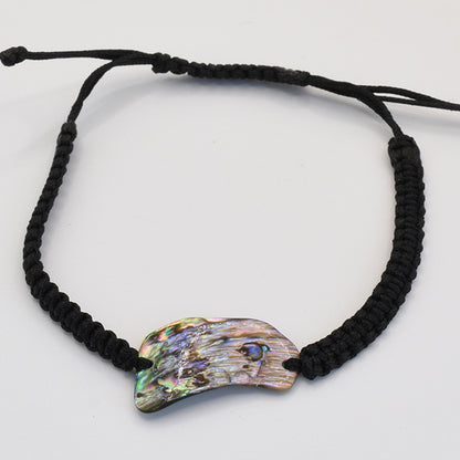 The Salty Dreamers Bracelet | Paua Shell Uru features a handmade black braided cord and a curved New Zealand abalone shell centerpiece with natural iridescent patterns, shown on a plain white background.