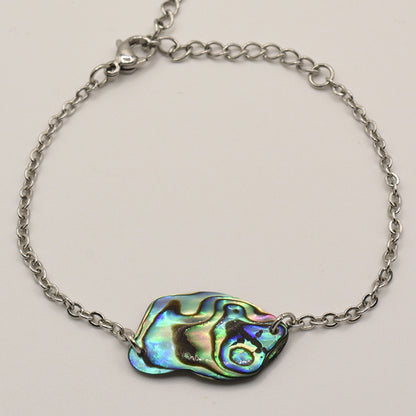 The Salty Dreamers Bracelet | Paua Shell Tumanako features a handcrafted silver chain, an iridescent abstract pāua shell centerpiece, and a lobster clasp, displayed on a plain light background. Inspired by New Zealand craftsmanship.