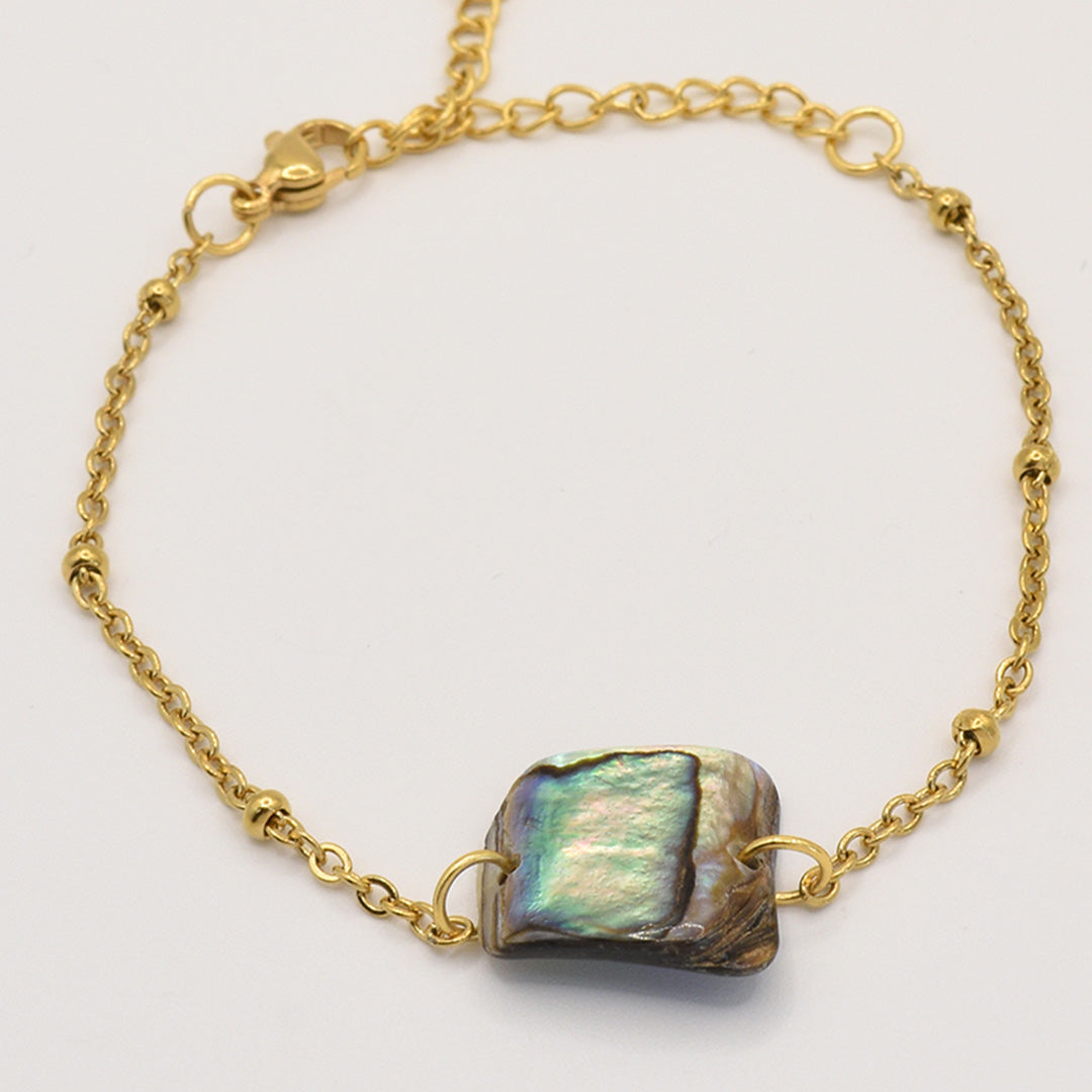 The Bracelet | Paua Shell Pae by Salty Dreamers features a gold chain and rectangular paua shell centerpiece with blue-green iridescence, highlighting handmade New Zealand jewelry against a plain light background.