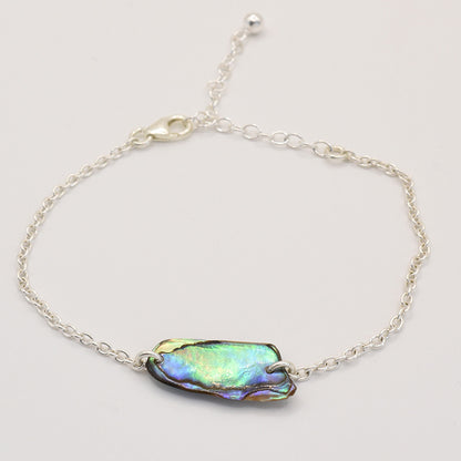 The Bracelet | Paua Shell Toi by Salty Dreamers features a delicate handmade silver chain with an iridescent New Zealand abalone shell centerpiece, adjustable lobster clasp, and is showcased on a plain white background.