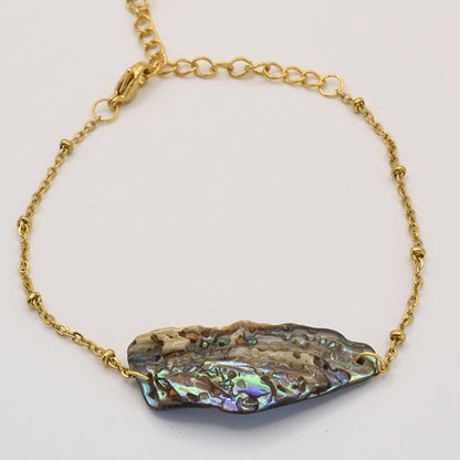 Salty Dreamers Bracelet | Paua Shell Takaro features a gold chain and a striking, iridescent paua shell centerpiece with natural purple, green, and blue hues—an exquisite piece of handmade New Zealand jewelry.