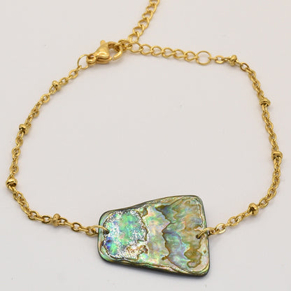 The Salty Dreamers Bracelet | Paua Shell Whakaora is a delicate gold chain bracelet with an iridescent, irregular pāua shell centerpiece, lobster clasp, and adjustable extender.