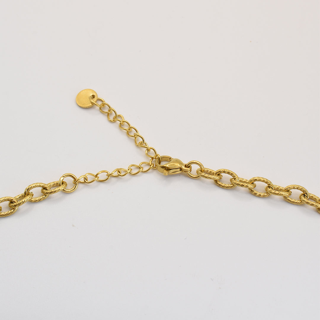 A close-up of Salty Dreamers Necklace | The Pearl, crafted from gold stainless steel with textured oval links and an adjustable extender clasp, displayed on a plain white background.