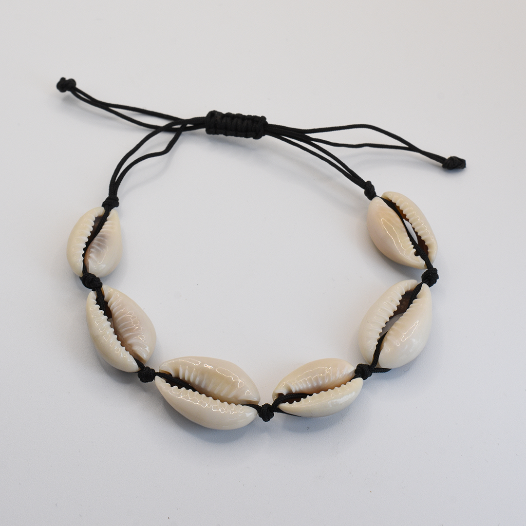 The Salty Dreamers Bracelet | Cowrie Away Black features six white cowrie shells on black cord with an adjustable knot, handmade and displayed on a plain white background.