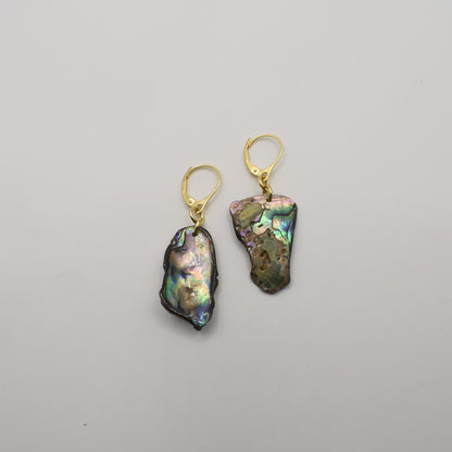 The Salty Dreamers Earrings | Paua Shell Marie feature two asymmetrical iridescent paua shell pieces with gold-plated silver lever-back hooks, shown on a plain white background.