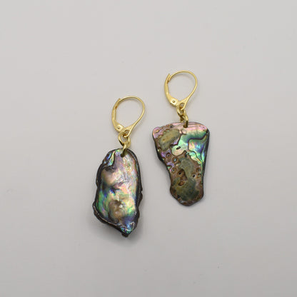 The Salty Dreamers Earrings | Paua Shell Marie feature irregular, iridescent paua shell pendants with gold lever-back hooks, elegantly displayed on a plain white background—a stunning piece of New Zealand jewelry.
