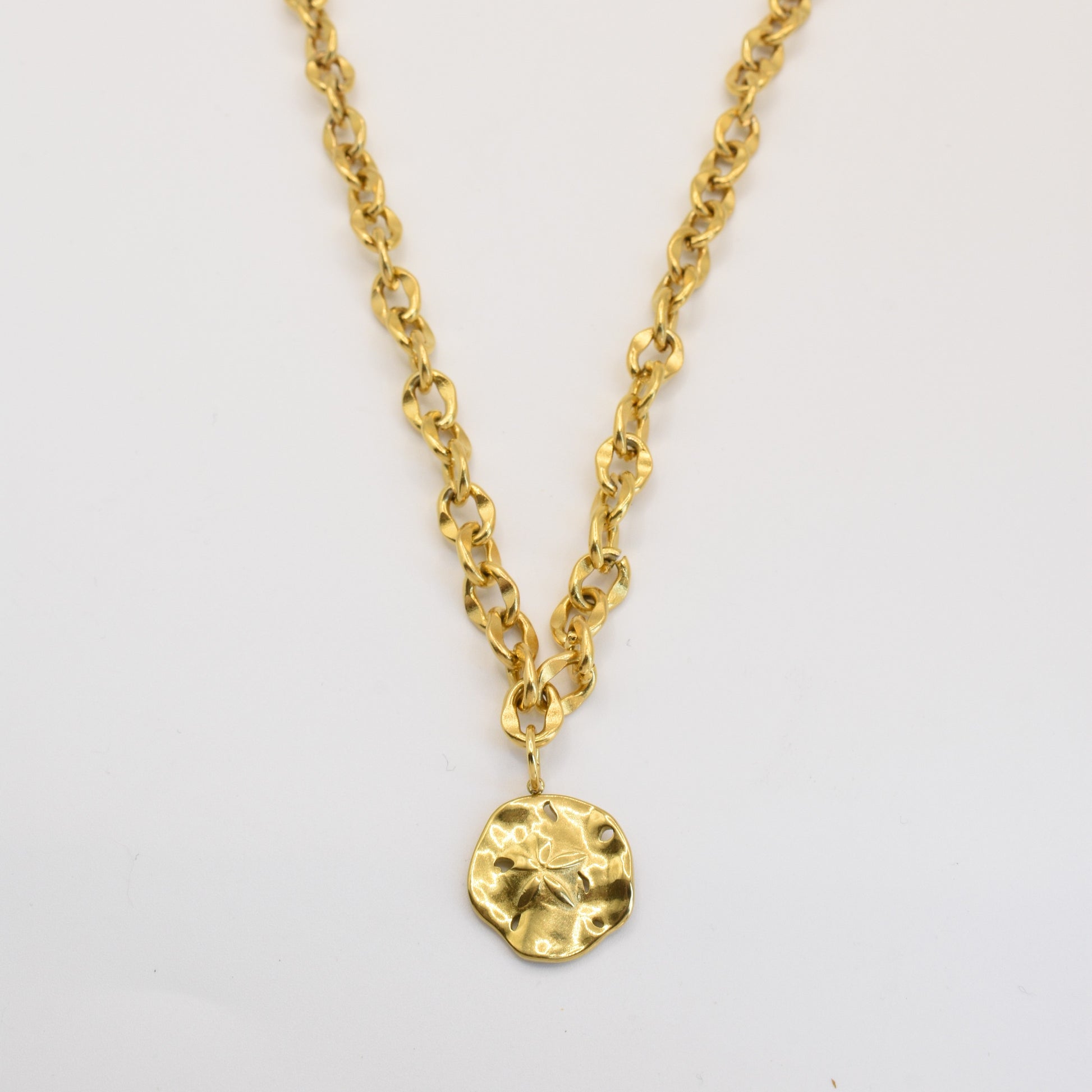 The Salty Dreamers Necklace | Ocean Dollar Gold features large gold links and a round, hammered pendant at the center. This handmade piece is showcased against a plain white background.
