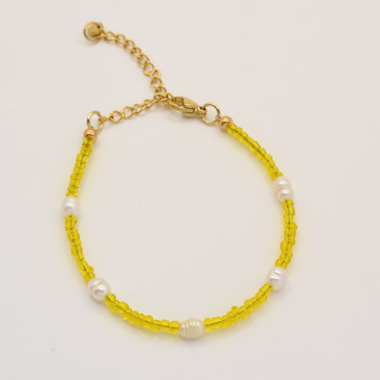 The Salty Dreamers Bracelet | Sunrise features delicate yellow glass beads with evenly spaced white pearls, finished with a gold chain and adjustable clasp, shown on a white background.