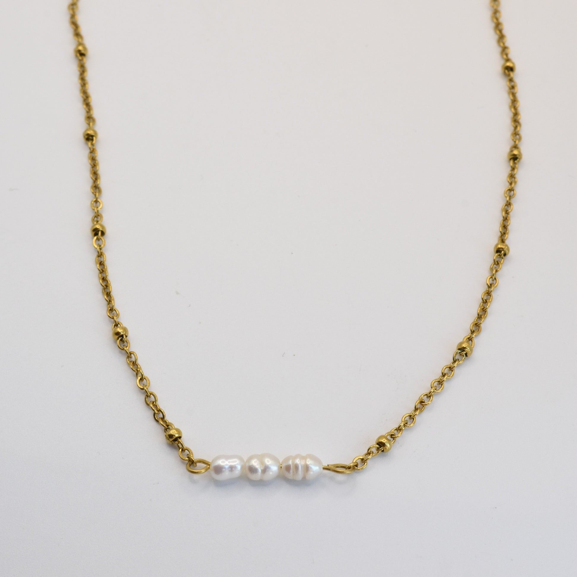 The Pretty Pearly Gold necklace by Salty Dreamers features a delicate gold chain with three small freshwater pearls in a row, shown on a plain white background.