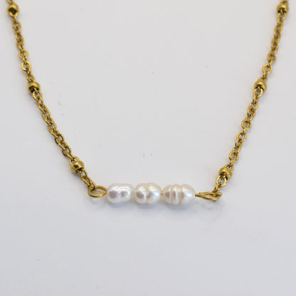 The Pretty Pearly Gold Necklace by Salty Dreamers features a delicate gold chain with three small, irregular freshwater pearls in a row, showcased on a simple white background.