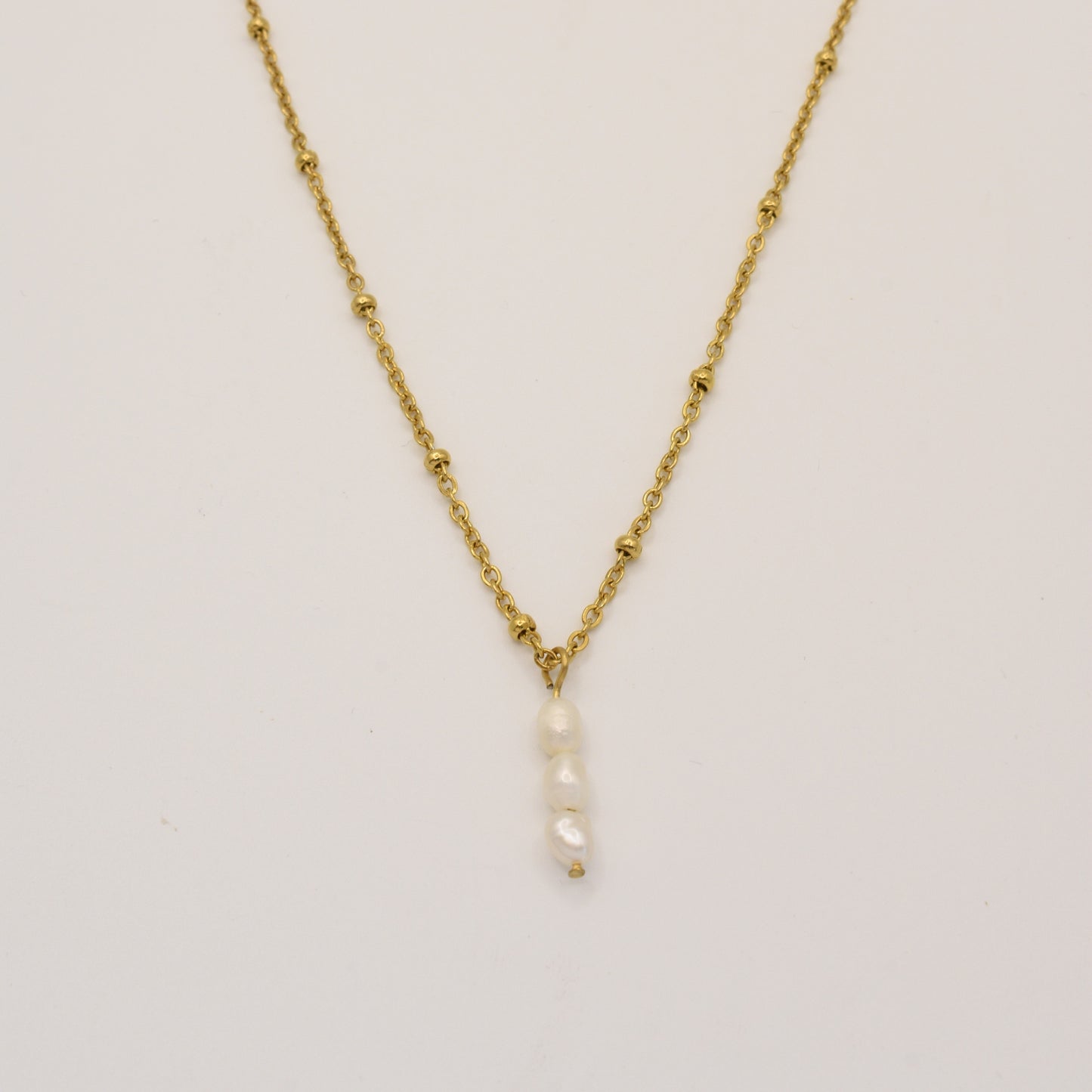 The Necklace | Cutie Pearlies by Salty Dreamers features a delicate gold chain with small bead accents and a handmade pendant of four vertically stacked white pearls, shown against a plain white background.