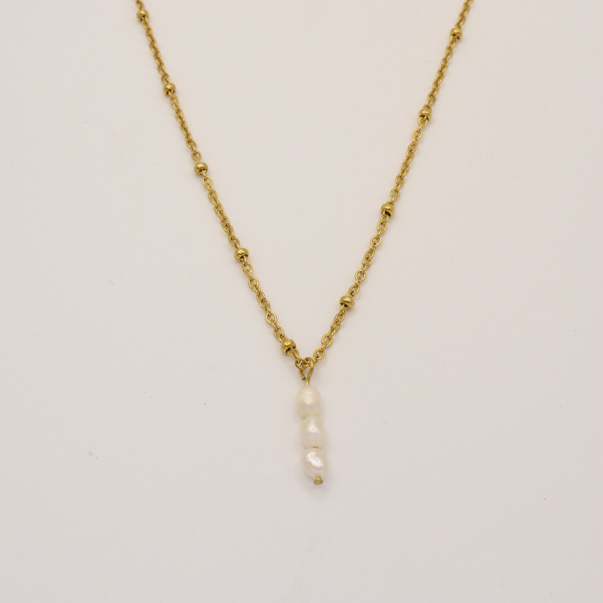 The Necklace | Cutie Pearlies by Salty Dreamers features a delicate gold chain with small bead accents and a handmade pendant of four vertically stacked white pearls, shown against a plain white background.