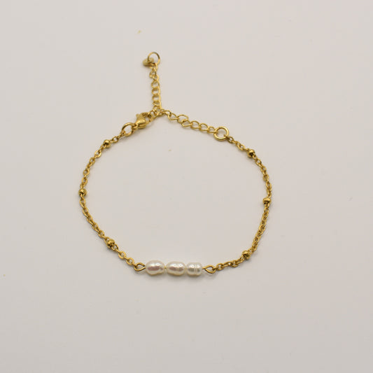The Pretty Pearly Gold bracelet by Salty Dreamers features a gold chain with three small white pearls, adding coastal charm to your jewelry collection. Displayed on a plain white background.