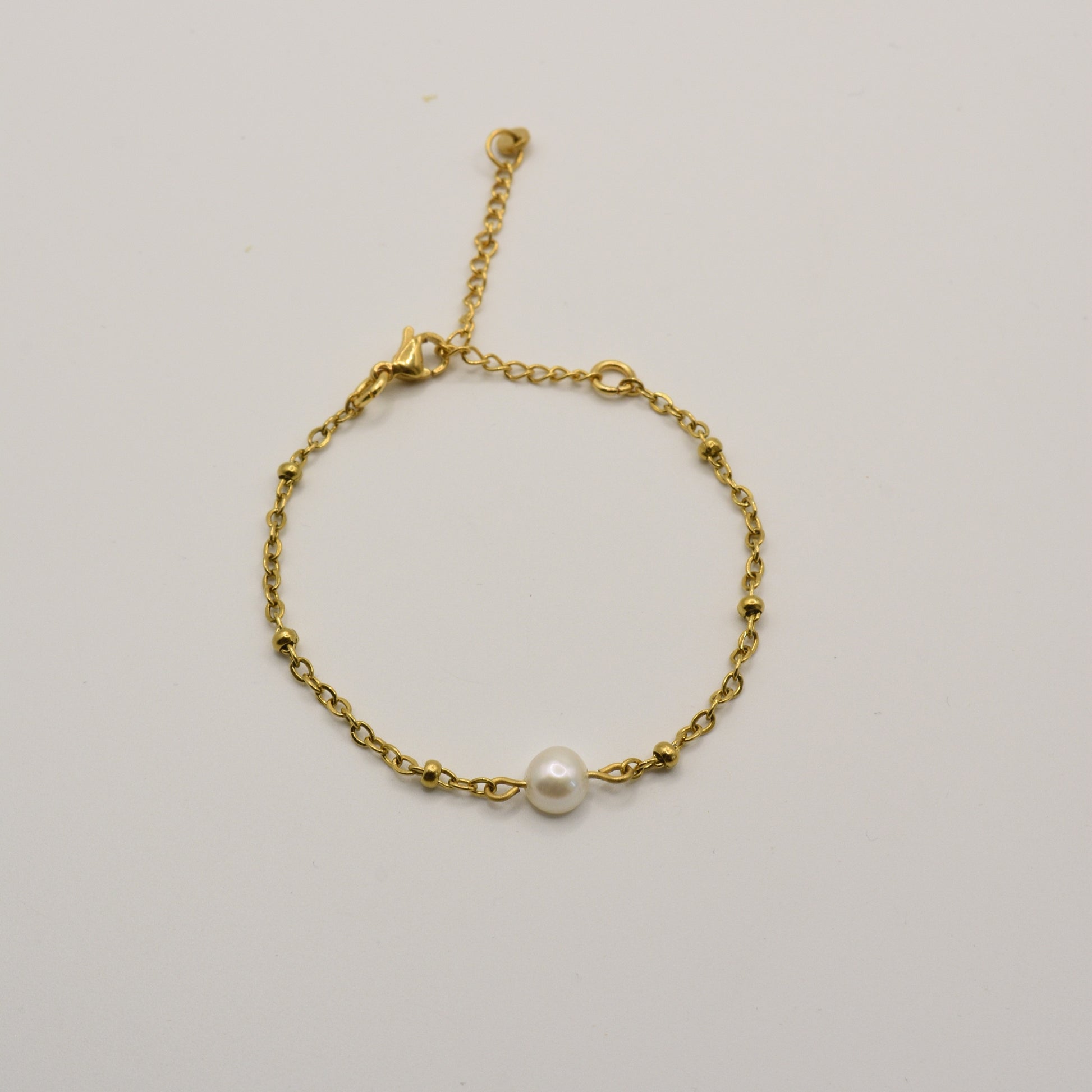 The Bracelet | Cutie Pearly Gold by Salty Dreamers features a delicate gold chain with small beads and a central white pearl, handmade for minimalist surfer style. Shown against a plain white background.