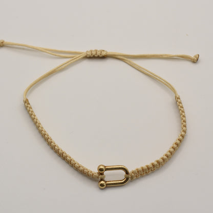 The Salty Dreamers Bracelet | Sailors Love Beige is a handmade macramé bracelet in beige with a small gold U-shaped clasp, inspired by classic sailor shackle bracelets and displayed on a plain white background.