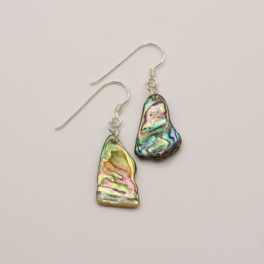 Salty Dreamers Earrings | Paua Shell Ruru feature handmade silver dangle earrings with irregular, iridescent abalone (paua) shell pieces set on silver hooks, displayed against a light background.