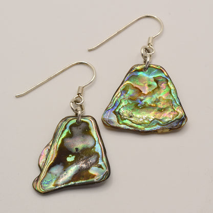 Earrings | Paua Shell Kea by Salty Dreamers—irregular, iridescent New Zealand pāua shell dangle earrings with silver hooks, displayed on a plain light background.