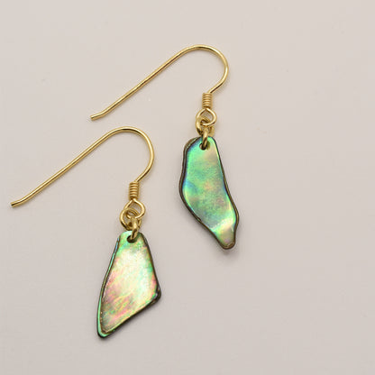 Salty Dreamers’ Paua Shell Uru earrings feature gold hooks and iridescent, irregular pāua shell pendants—New Zealand sea opal—shown on a light beige background.
