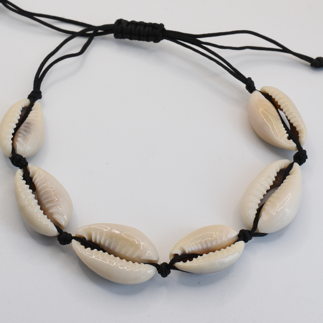 The Salty Dreamers Bracelet | Cowrie Away Black features six cream cowrie shells on an adjustable black cord and is shown on a white background.