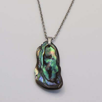 The Salty Dreamers Necklace | Paua Shell Takaro is a handmade silver chain necklace with a polished, iridescent pāua shell pendant showing green, blue, and purple hues on a plain white background.