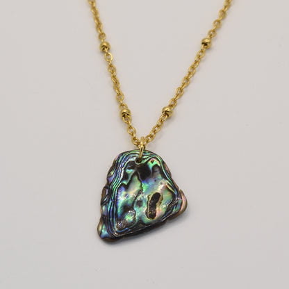 The Necklace | Paua Shell Moana by Salty Dreamers is a gold chain necklace featuring an iridescent, irregularly shaped pāua shell pendant—a striking piece of New Zealand jewelry shown on a plain white background.