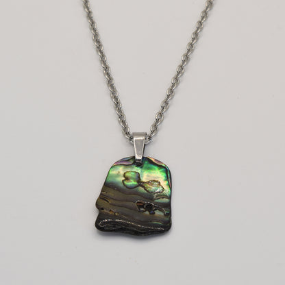 The Salty Dreamers Necklace | Paua Shell Kowhai features a handmade silver chain with an iridescent pāua shell pendant in green, blue, and brown tones, shown on a plain white background.