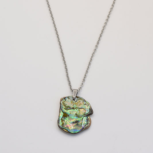 The Necklace | Paua Shell Kaukau by Salty Dreamers features an iridescent, irregular pāua shell pendant on a silver chain—a handmade piece that showcases natural beauty, displayed on a plain white background.