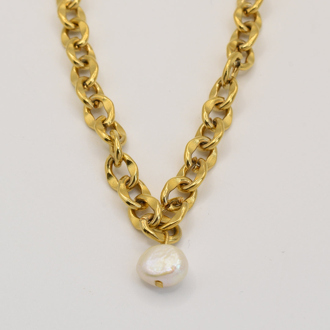 The Pearl Necklace by Salty Dreamers features large gold links and a single white irregular pearl pendant, showcased on a plain light background.