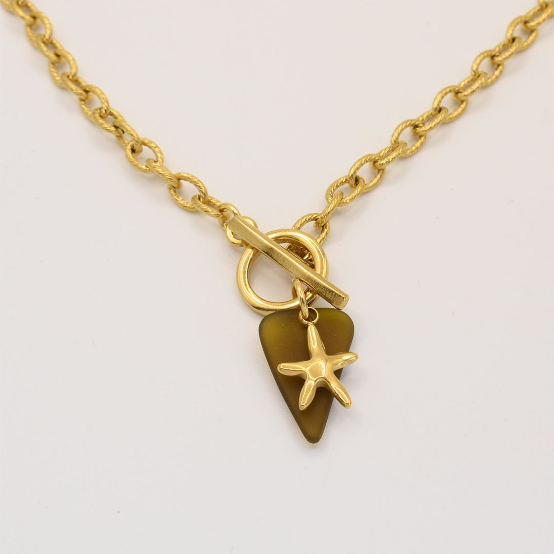 The Salty Dreamers Necklace | Star Sea Glass features a golden stainless steel chain with a toggle clasp, adorned with a genuine brown sea glass pendant and a gold starfish charm.