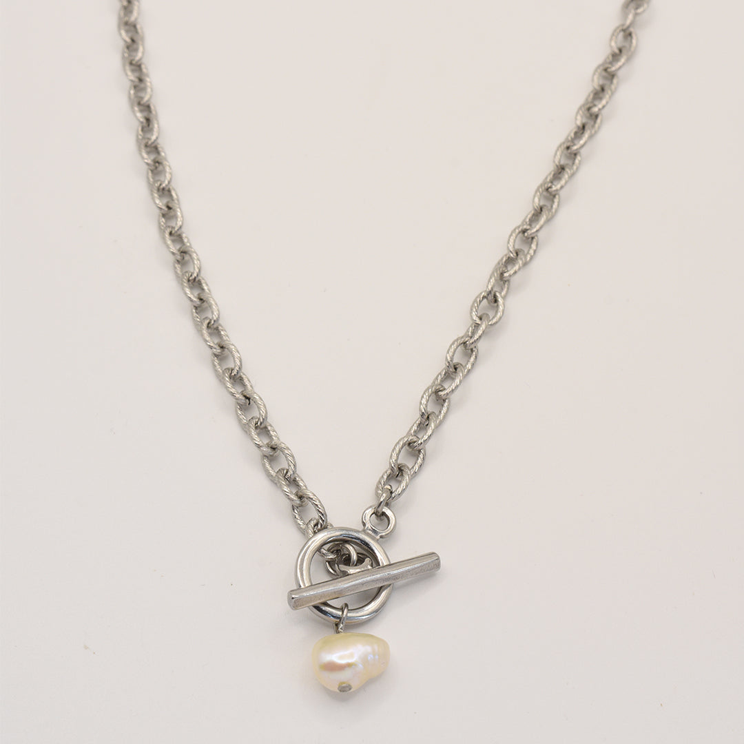The Cutie Pearl necklace by Salty Dreamers is a modern handmade silver chain with a central toggle clasp, featuring a single irregular freshwater pearl charm.