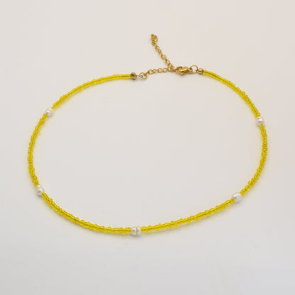 The Salty Dreamers Necklace | Starfish features delicate yellow beads, evenly spaced white pearls, and a gold adjustable clasp, all handmade in Germany and shown on a plain white background.