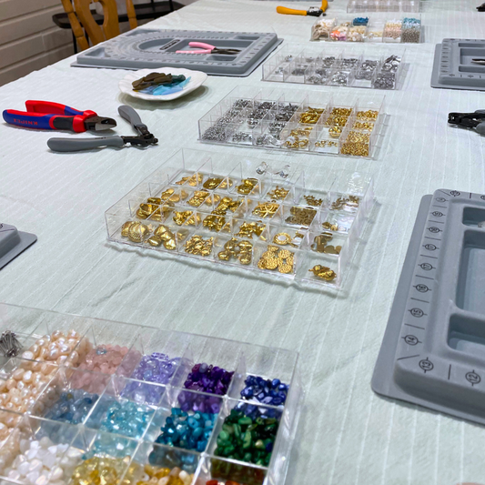 At Salty Dreamers' Workshop Ocean Jewellery in Kiel, a white-clothed table displays colorful beads, gold findings, tools, and bead boards—everything you need to create your own jewelry.
