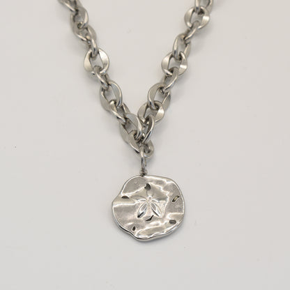 The Salty Dreamers Necklace | Ocean Dollar Silver features a chunky silver chain with a round, textured sand dollar pendant and cut-out details, shown on a plain light background.