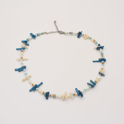 The Salty Dreamers Necklace | Ocean Bamboo Blue is a handmade piece with irregular blue and cream stick beads, turquoise and brown rounds, and white pearls, finished with a silver adjustable clasp. Displayed on a white background.