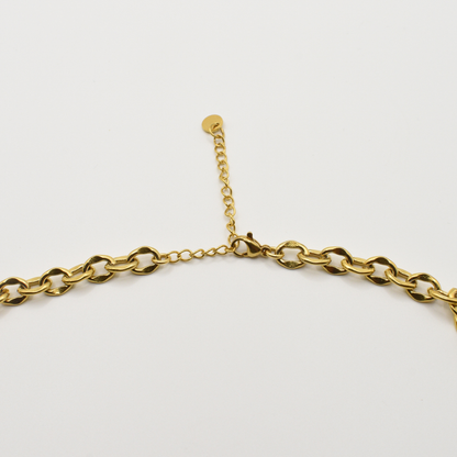 A close-up of the Salty Dreamers Necklace | Paua Shell Tautahi—a gold chain with clasp and extender, showcasing a beautiful abalone pendant—displayed on a white background.