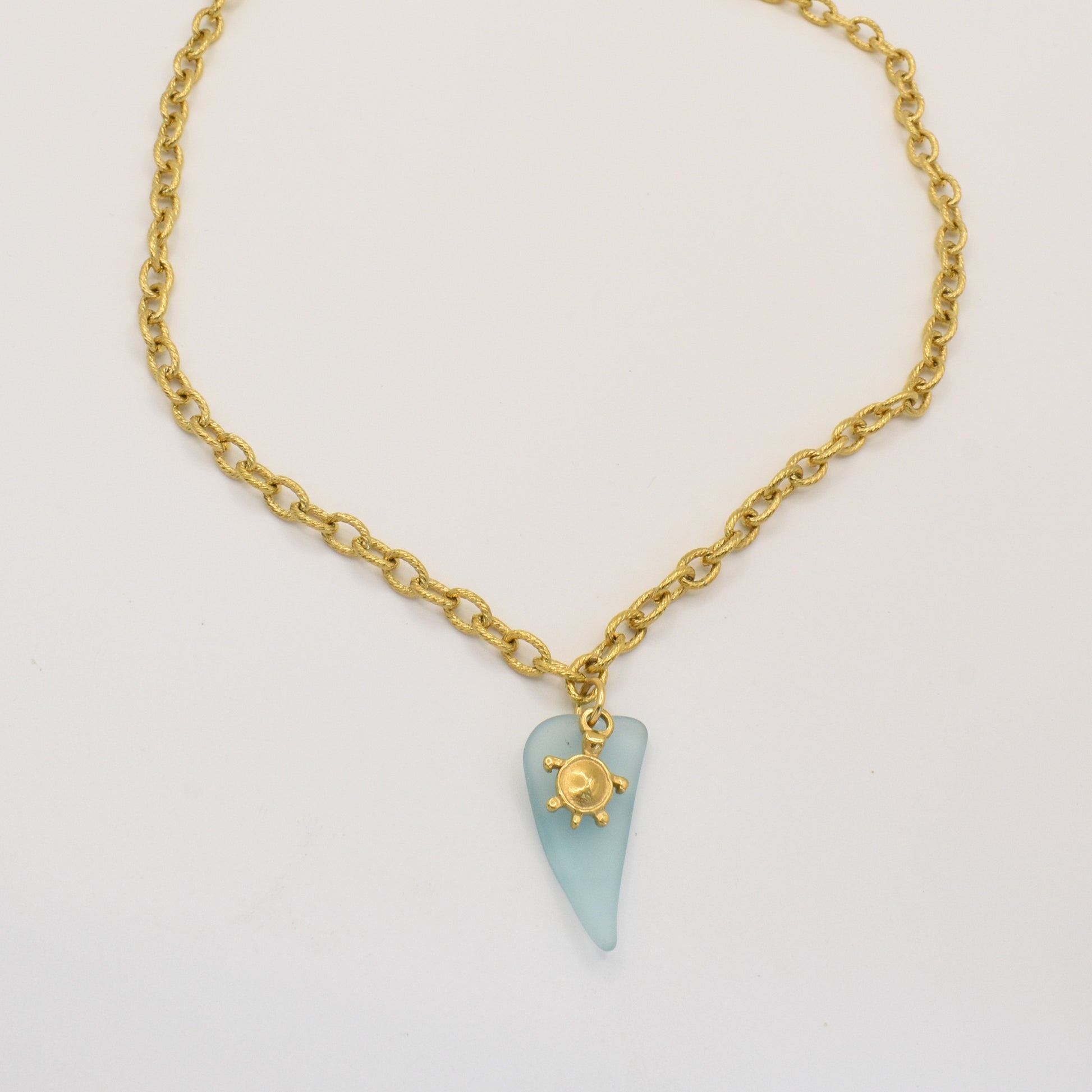 The Salty Dreamers Necklace | Turtle Sea Glass features a blue sea glass pendant with a gold turtle charm, beautifully showcased on a white background.