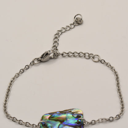 The Salty Dreamers Bracelet | Paua Shell Marama is a handmade silver chain bracelet with an iridescent abalone centerpiece, lobster clasp, and adjustable extender chain, shown on a plain white background.